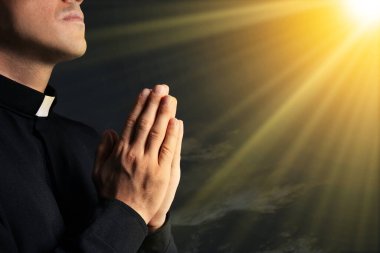 Kutsal ışıkla aydınlatılan rahip güzel gökyüzüne karşı dua ediyor, yakın plan.