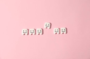 Pembe arka planda küçük diş figürleri, düz yatış