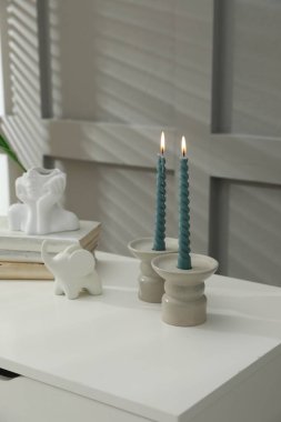 Mum ve yanan mumlar gri duvarın yanındaki masada.