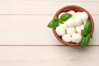 Lezzetli mozzarella peynirli toplar kasede ve fesleğen açık ahşap masada, üst manzara. Metin için boşluk