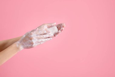 Açık pembe arka planda ellerini sabunla yıkayan kadın, yakın plan. Metin için boşluk