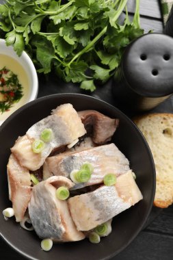 Lezzetli ringa balıkları. Siyah ahşap masa üzerinde yeşil soğanlar.