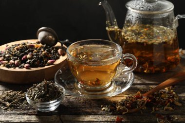 Bitki çayı ve kuru yaprakları ahşap masaya serpmek, yakın plan.