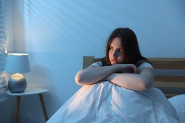 Yatakta uykusuzluk çeken sinirli genç bir kadın.