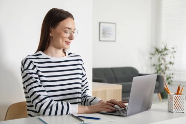 İçerideki masada dizüstü bilgisayar kullanan bir kadın. Kendi kendine çalışma.