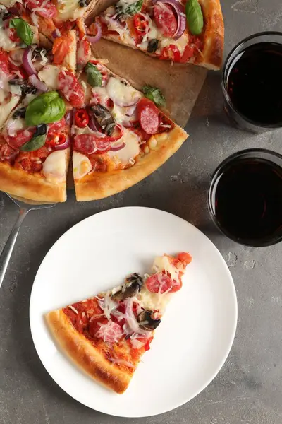 Gri masada servis edilen ince tütsülenmiş sosisli lezzetli bir pizza.