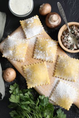 Pişmemiş ravioli, mantar ve sos siyah masada, düz yatıyordu.