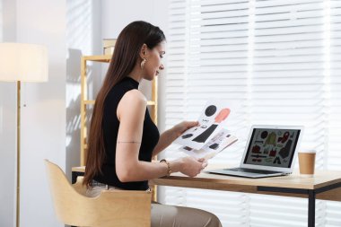 Profesyonel stilist iç mekanda dizüstü bilgisayarla kolaj yapıyor.