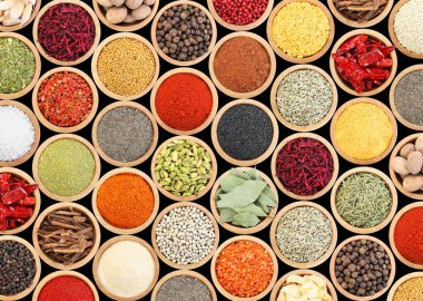 Siyah arka plandaki kaselerde farklı aromatik baharatlar dizisi.