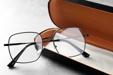 Şık gözlüklü çanta ve gri masadaki temizlik bezi, yakın plan.