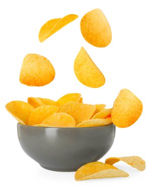 Lezzetli patates cipsleri beyaz arka planda kaseye düşüyor.