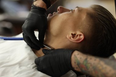 Berber dükkanında müşteriyle çalışan profesyonel berber, yakın plan.