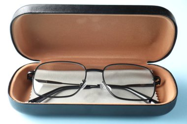 Açık mavi arka planda şık gözlüklü ve temiz giysili çanta, yakın plan