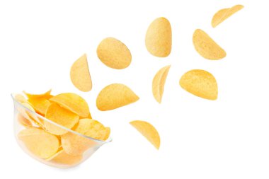 Lezzetli patates cipsleri beyaz arka planda kaseye düşüyor.