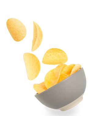 Lezzetli patates cipsleri beyaz arka planda kaseye düşüyor.