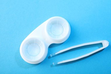 Mavi arka planda kontak lensler ve cımbızlar düz konum