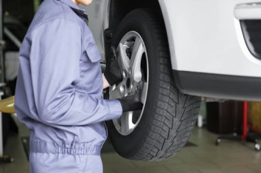 Tamirci araba servisinde lastik değiştiriyor, yakın plan.