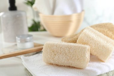 Beyaz masada farklı banyo süngeri ve havlular, yakın plan.