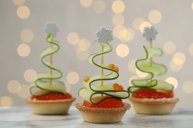 Arka planı bulanık ışıklarla kaplı beyaz mermer masa üzerinde lezzetli kanepeler, yakın plan. Bokeh etkisi