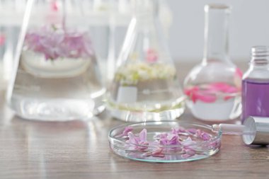 Lüks parfüm yapıyorum. Temel yağlar cam süslemede ve çiçekler açık ahşap masada, yakın plan