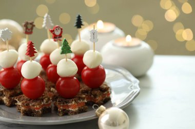 Arka planda bulanık ışıklarla beyaz masa üzerinde lezzetli kanepeler ve Noel dekoru, yazı için yer var. Bokeh etkisi
