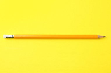 Sarı arkaplanda keskin bir grafit kalem, üst görünümde.