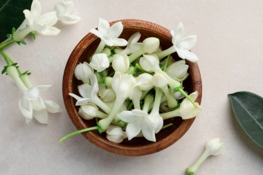 Üzerinde yasemin çiçekleri olan bir kase bej masa, düz uzanmış