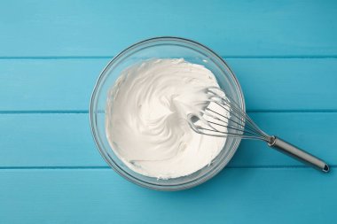Açık mavi ahşap masada çırpılmış ve çırpılmış krema.