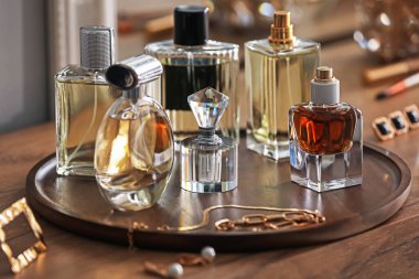 Farklı parfüm şişeleri ve aksesuarlar ahşap masada, yakın plan.