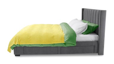 Beyaz arka planda güzel çarşaflarla yapılmış bir yatak.