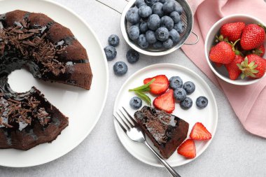 Açık gri desenli masada çilekli ve yaban mersinli lezzetli çikolatalı kek, düz konum.