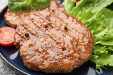 Lezzetli hamburger köfteleri, domates, marul ve baharatlar masada, yakın plan.