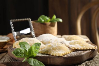 Ahşap masada pişmemiş ravioli ve fesleğen, yakın plan. Metin için boşluk
