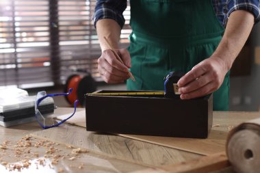 İçerideki ahşap masada bant ile ölçüm yapan adam, yakın plan.