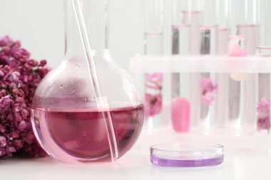 Lüks parfüm yapıyorum. Temel yağlar cam eşyalar ve çiçekler beyaz masada, yakın plan.