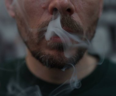 Arka planda sigara içen adam, yakın plan.