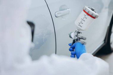 Kaportacıda çalışan bir işçi araba boyuyor, yakın plan.