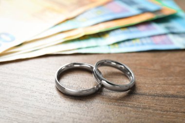 Gümüş alyanslar ve euro banknotları ahşap masada, yakın plan.