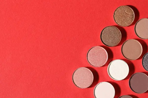 Kırmızı arka planda güzel göz farı dolgu kapları, düz yatış. Metin için boşluk