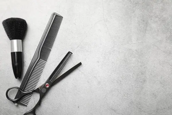 Gri masadaki farklı kuaför aletleri, düz yatış. Metin için boşluk