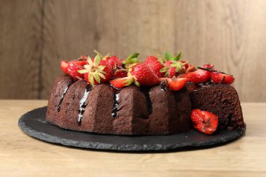 Çilekli lezzetli çikolatalı kek, ahşap masada, yakın plan.