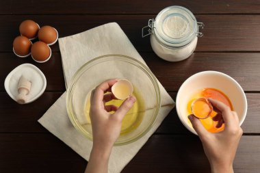Tahta masada yumurta sarısını beyazdan ayıran kadın.