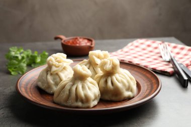 Gri masadaki sosla servis edilen lezzetli khinkali, yakın plan.