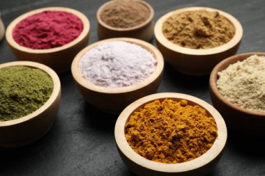 Siyah masadaki farklı süper yiyecek tozları, yakın plan.