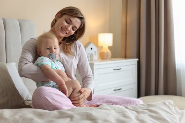 Yatma vakti. Mutlu bir anne ve evde yatağında küçük sevimli bir bebeği var, mesaj atmak için yer var.