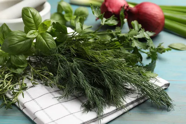 Mavi ahşap masada farklı otlar ve baharatlar, yakın plan.