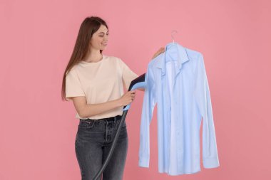 Gülümseyen kadın pembe arka planda buharlı gömlek