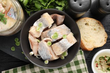 Lezzetli ringa balıkları. Siyah ahşap masa üzerinde yeşil soğanlar.