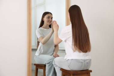 Güzel bir kadın aynada kendine bakıyor.