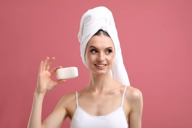 Pembe arka planda sabun çubuğuyla gülümseyen kadın.